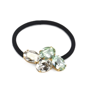 Detailed macro view of oval crystals in gold claw settings on a black elastic hair tie