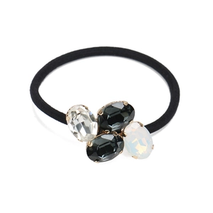 Detail of oval crystal rhinestones with gold prong setting on black elastic hair tie