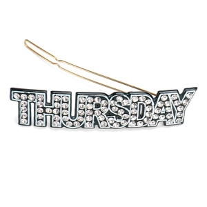 Détail d'une pince à cheveux dorée avec texte THURSDAY orné de strass blancs brillants