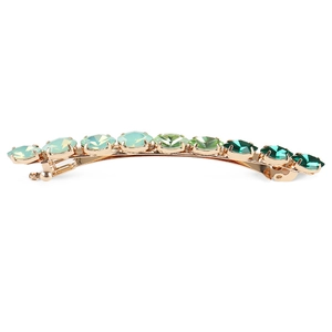 Vue macro d'une barrette à cheveux dorée avec des cristaux de strass vert dégradé