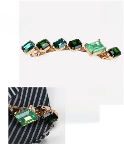 Gros plan sur les cristaux verts géométriques fixés sur une barrette dorée pour femmes