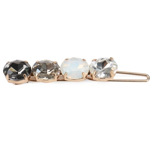 Macro detail of a golden hair clip with four faceted crystals in grey and white