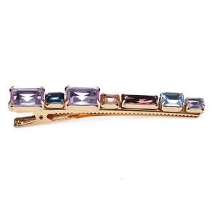 Detail view of gold hair clip with multi-color rectangular crystals and claw setting
