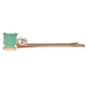 Détail de la pince à cheveux avec cristal vert rectangle et strass transparent