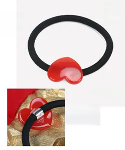 Dettaglio del ciondolo a cuore in acetato rosso su un elastico nero per capelli da donna