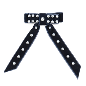 Détail du nœud papillon en velours bleu marine orné de perles et de longs rubans