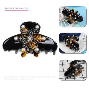 Detail of black acetate hair claw clip featuring pearl snowflake and rhinestone patterns