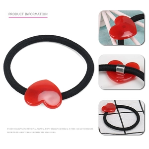 Dettaglio di cuore in resina rossa su elastico nero per capelli con fermagli in metallo
