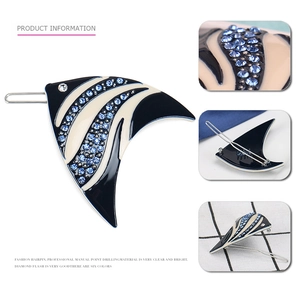 Detailed view of fish-shaped acetate hair clip with rhinestones and striped texture