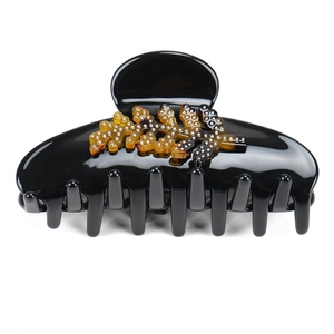 Macro shot of large black acetate hair claw with amber tree leaf pattern and silver dots