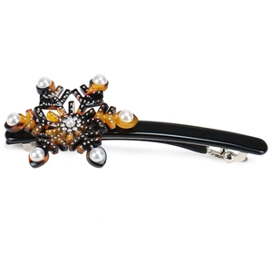 Macro detail of snowflake hair clip with tortoise shell pattern and pearl accents