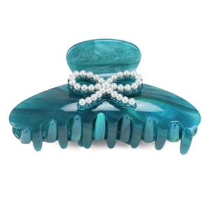 Detail of teal marble acetate hair claw clip featuring white pearl bow design
