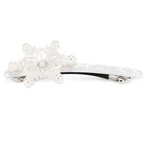 Macro detail of snowflake hair clip featuring white acetate, faux pearls, and rhinestones