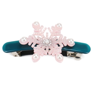 Close-up of pink snowflake hair clip with white pearls and crystals on teal base