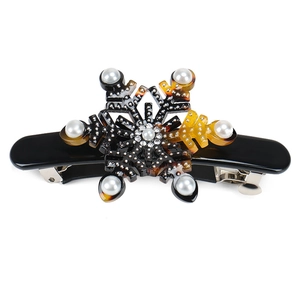 Detail of elegant snowflake hair clip featuring tortoiseshell resin and faux pearls