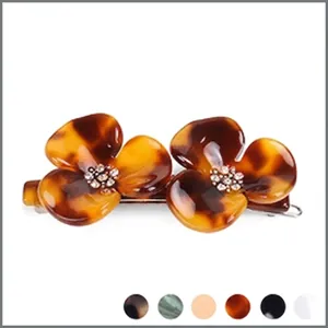 Dettaglio della pinza per capelli in acetato con motivo tartarugato marrone e fiori di cristallo