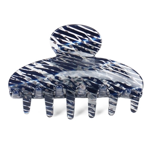 Vue détaillée d'une pince à cheveux en acétate bleu et blanc montrant la texture polie