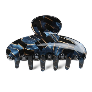 Détail du clip à cheveux avec texture marbre bleu foncé et motifs de veines dorées