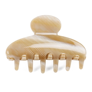 Gros plan sur la pince à cheveux en acétate marbré beige sur un fond blanc neutre