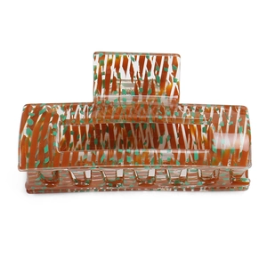 Detail view of large acetate hair claw clip featuring brown stripes and green pattern