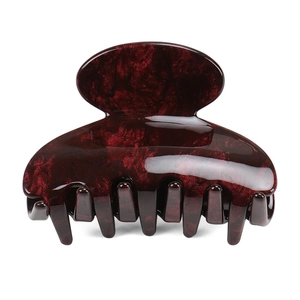 Macro view of a deep wine red cellulose acetate hair claw clip with marble texture