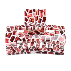 Detailed macro view of acetate hair claw clip featuring red and white mosaic pattern