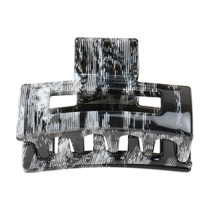 Close-up of a rectangular hair claw clip with black and white marble pattern texture
