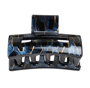 Detail of hollow geometric hair claw featuring navy marble texture and gold vein pattern