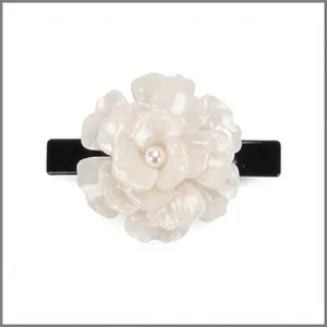 Dettaglio di un fermaglio per capelli a fiore in resina crema con perla e base nera