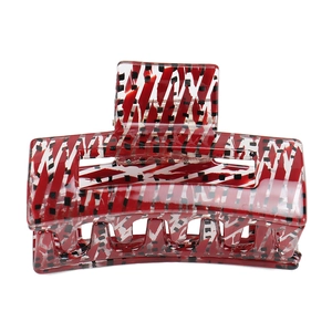 Detail of a geometric hollow hair claw clip with red and white striped acetate patterns