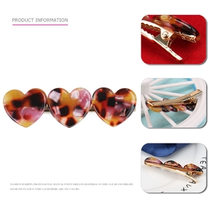 Macro detail of tortoiseshell acetate heart hair clip with golden metal alligator base