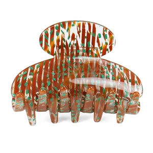 Detail view of acetate hair claw clip with brown stripes and green pattern texture