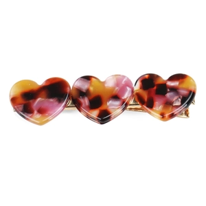 Detailed close-up of tortoise shell heart hair clips with golden metal duckbill base