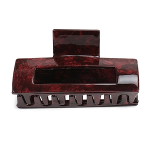 Macro detail of large acetate claw clip showing vintage red marble texture and strong teeth
