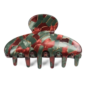 Détail d'une grande pince à cheveux en acétate marbré avec motifs rouge, vert et doré