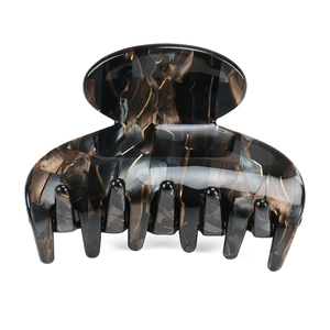 Detailed close-up of acetate hair claw clip featuring black and gold amber marble texture