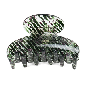 Detail view of acetate claw clip with green striped pattern and glossy finish