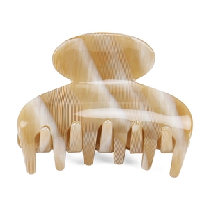 Detail view of cream marble hair claw clip with vertical ridges and secure spring