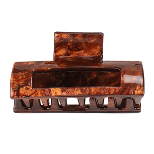 Macro detail of amber marble pattern hair claw clip with glossy acetate finish