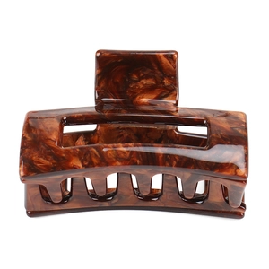 Close-up of a medium hollow geometric hair claw with a polished dark brown amber texture