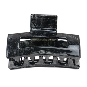Detail of a rectangular hollow hair claw with a black and gray marble ink pattern