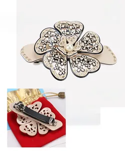 Detailed view of beige camellia acetate hair clip with pearls and sparkling rhinestones