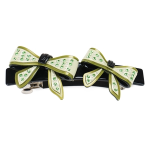 Detail of a bow hair clip with green rhinestones and cream-green acetate pattern
