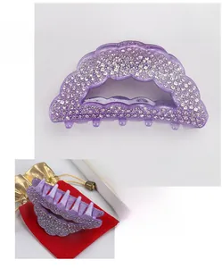 Vue détaillée d'une pince à cheveux en acrylique violet avec strass et sac cadeau rouge