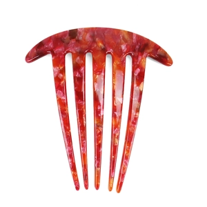 Detail view of acetate hair comb with marble texture in red, pink and orange tones