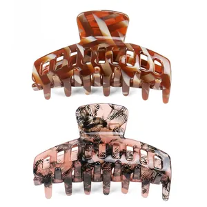 Detail view of two acetate hair claws in amber tortoise and marble patterns