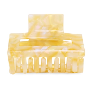 Macro detail of square acetate hair claw with pale yellow marble texture and teeth