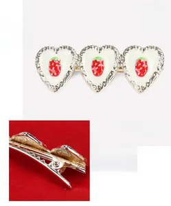 Detailed view of alloy hair clip with three strawberry heart patterns and duckbill back
