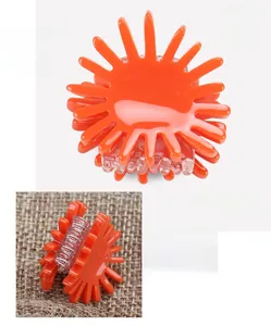 Detail view of small orange sunflower hair claw clip made of premium cellulose acetate