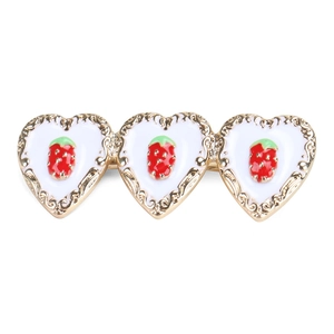 Detail view of heart-shaped hair clip with red strawberry motif on white enamel base